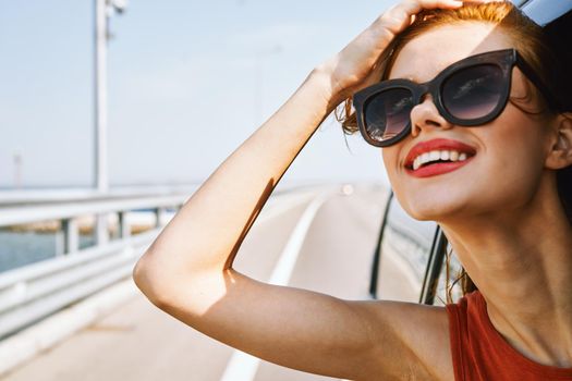 cheerful woman peeking out of the car window trip adventure lifestyle. High quality photo