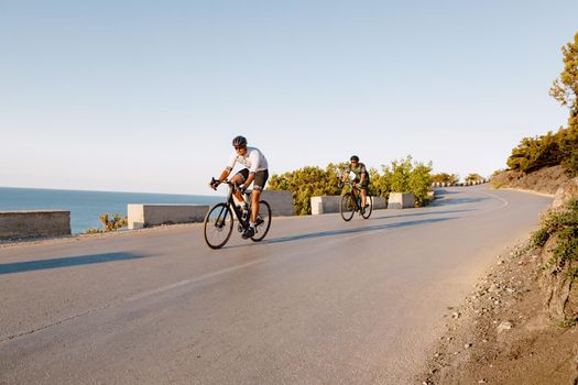 Two professional male cyclists riding their racing bicycles in the morning together on coastal road