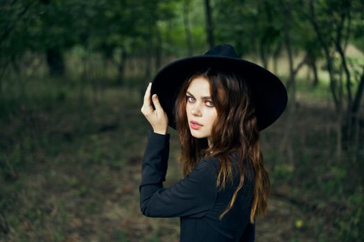 woman in the forest in a black hat gothic style Witch costume. High quality photo