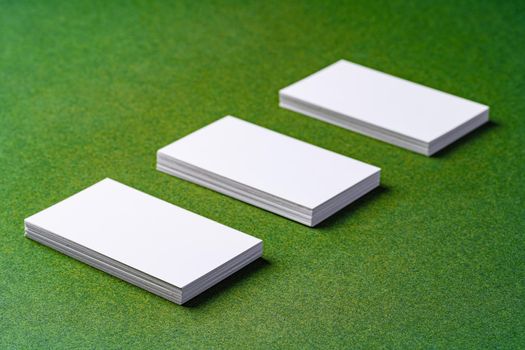 Stacks of white business cards on dark green background, close up