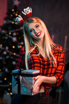 Christmas, x-mas, New year, winter, happiness concept - smiling woman in santa helper hat with gift box. Funny people. Christmas party at home