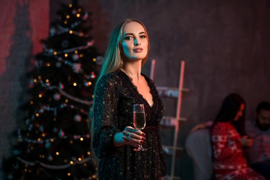 Beautiful young woman with glass of champagne at Christmas party. Funny people.