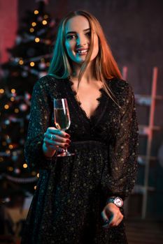 Beautiful young woman with glass of champagne at Christmas party. Funny people.