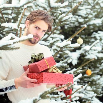 Sexy man holding Christmas gift in snow wood outdoor. Merry Christmas and happy new year. Macho with presents on winter day.