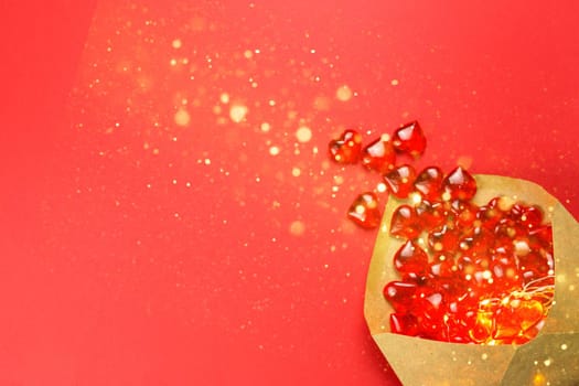 Glass hearts spill out of an open envelope on a red background. Valentine's Day, love letter, declaration of love, acquaintance. Copy space, mock up