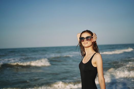 pretty woman in black swimsuit posing sun walking on the beach. High quality photo
