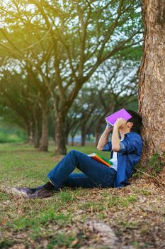 young man in stress situation when reading a book in the park