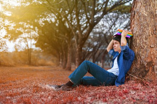 young man in stress situation when reading a book in the park