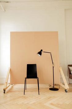 Big beige photo background with black chair and lamp near ready for photo session in big light room