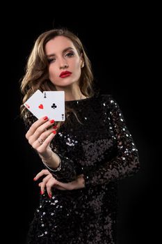 Young beautiful woman in black shiny dress holds poker cards in hands against a black background. The concept of gambling. Casino