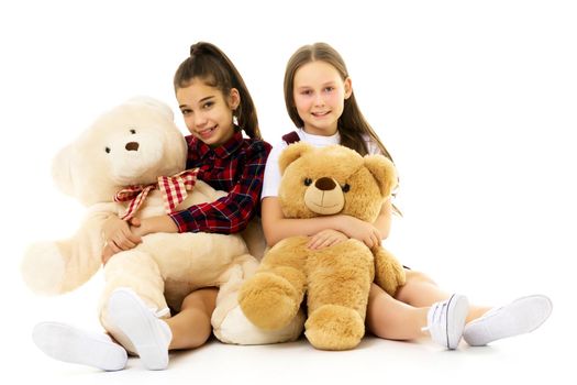 Little girl with toy. Two beautiful happy girls standing and embracing plushs toy in children room. Tenderness and beauty concept. Girls holds heap of teddy bears. Girl hugging teddybears, childhood.