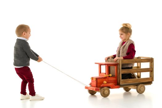 Brother and sister are playing with a toy car. The concept of happy childhood, people, harmonious development of the child in the family. Isolated on white background.