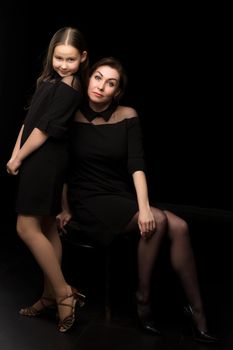 Happy family mom and little daughter, studio portrait.On black background