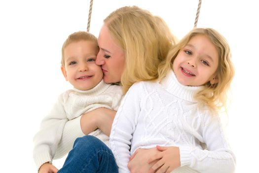 Family of Mother and Two Kids Sitting Together on Rope Swing, Smiling Mom Hugging and Kissing Her Little Son and Daughter Wearing Stylish Clothes, Family Portrait Isolated on White Background