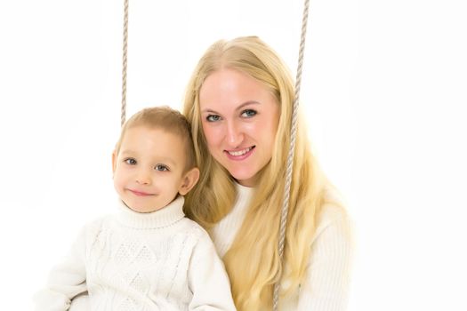 Happy Family of Mother and Two Kids Sitting Together on Rope Swing, Smiling Mom Hugging Her Son and Daughter Wearing White Sweaters and Jeans, Family Portrait Isolated on White Background