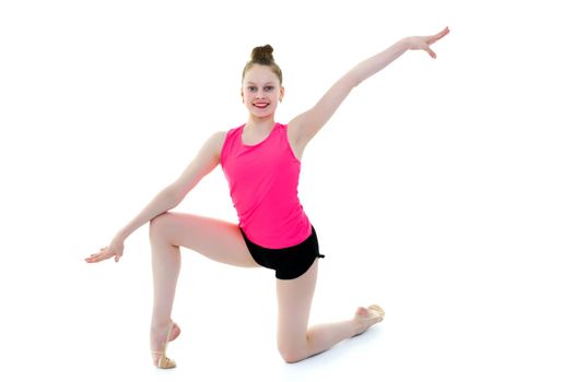 A girl gymnast performs an acrobatic element on the floor. The concept of childhood, sport, healthy lifestyle. Isolated on white background.