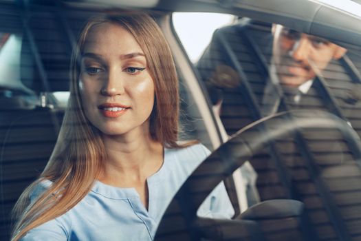 Attractive young woman sitting in new car in showroom close up