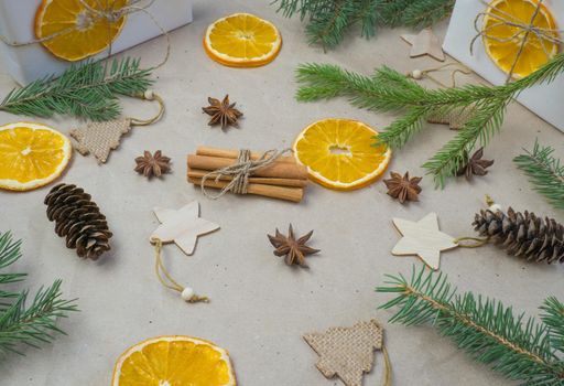 New Year's composition. On beige craft paper, gift boxes, dry orange slices, pine cones, cinnamon, cloves, spruce branches. Cozy Christmas concept