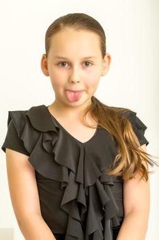 Cheerful little girl shows tongue. The concept of a happy childhood.