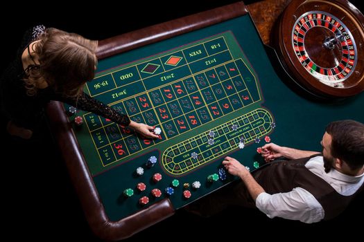 Croupier and woman player at a table in a casino. Picture of a classic casino roulette wheel. Gambling. Casino. Roulette. Poker. Top view of a green roulette table