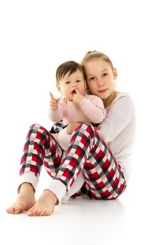 Two funny girls of different ages in the studio on a white background. The concept of a happy childhood. Isolated on white background.