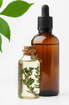 Essential oil in a small bottle with green leaf on white background, close up