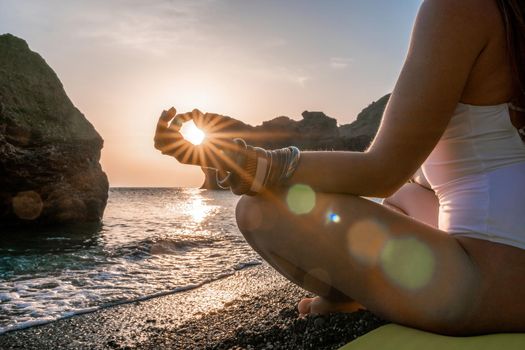 Young woman in swimsuit with long hair practicing stretching outdoors on yoga mat by the sea on a sunny day. Women's yoga fitness pilates routine. Healthy lifestyle, harmony and meditation concept.