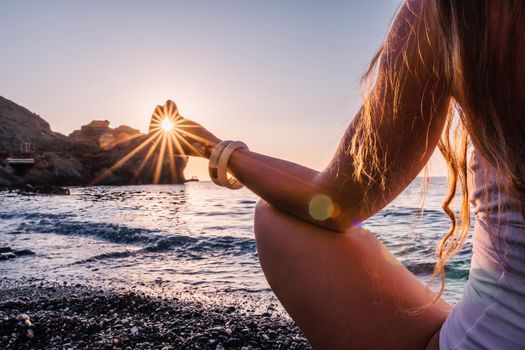 Young woman in swimsuit with long hair practicing stretching outdoors on yoga mat by the sea on a sunny day. Women's yoga fitness pilates routine. Healthy lifestyle, harmony and meditation concept.