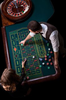 Croupier and woman player at a table in a casino. Picture of a classic casino roulette wheel. Gambling. Casino. Roulette. Poker. Top view of a green roulette table