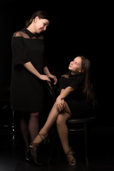 Happy family mom and daughter in the studio on a black background. The concept of love, childhood.