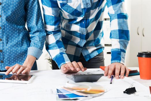 Designers working with color swatches and tablet computer at desk. Interior design, architectural decoration and renovation. Brainstorm, teamwork and creativity. Decorator workplace in design agency