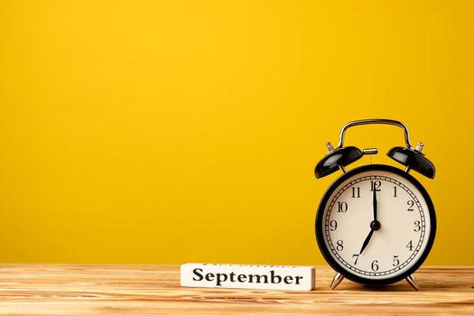 Back to school concept with alarm clock against yellow background