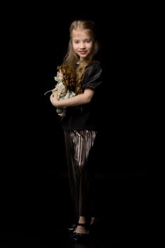 Cute little girl playing with a doll on a black background.