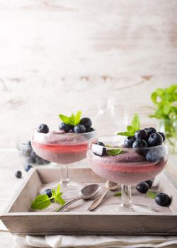 Glass of homemade healthy blueberry dessert with syrup and fresh berries.