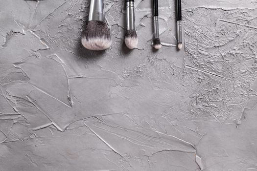 Top view of make-up brushes on grey background.