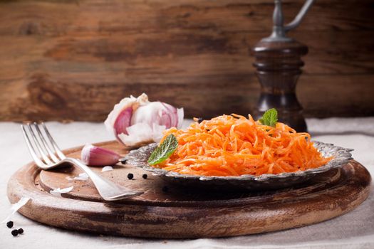 Spicy Korean style carrot salad on metal plate with spices. Selective focus. Rustic style.