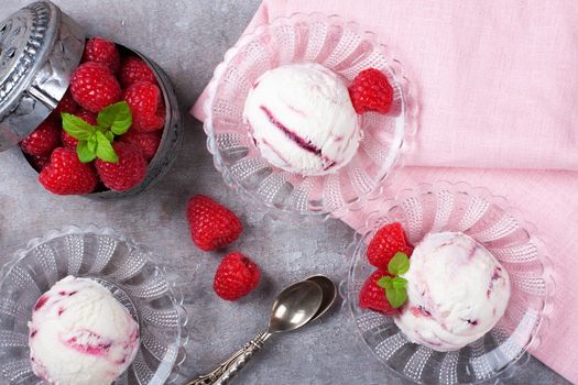 Delicious berry ice cream on glass plate decorated with fresh raspberries on vintage gray background. Top view. Party concept.