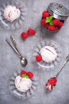 Delicious berry ice cream on glass plate decorated with fresh raspberries on vintage gray background. Top view. Party concept.