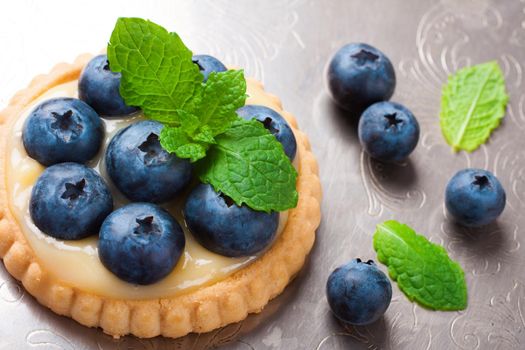 Shortbread home made tartlet filled with lime curd and blueberries on old vintage metal background. Holiday concept. Background with copy space.