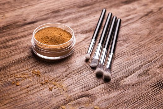 Mineral powder foundation with brush on a wooden background.