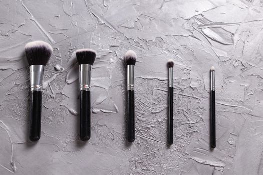 Top view of make-up brushes on grey background.