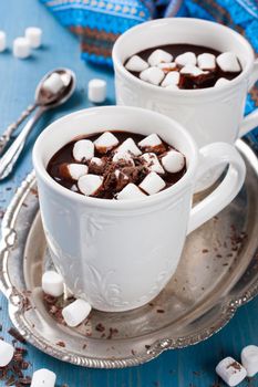 Chocolate almond milk with chocolate and marshmallow on blue background. Selective focus