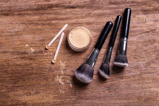 Mineral powder of different colors with spoon dispenser for make-up on wooden background.