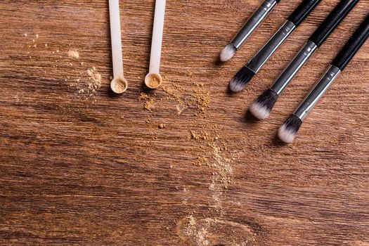 Mineral powder foundation with brush on a wooden background.