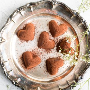 Handmade candies Tiramisu in eart shape on metal plate. Valentine's Day and Mother's Day concept. Top view.