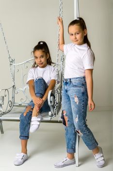 Two beautiful little girls near the swing. The concept of tenderness and beauty.