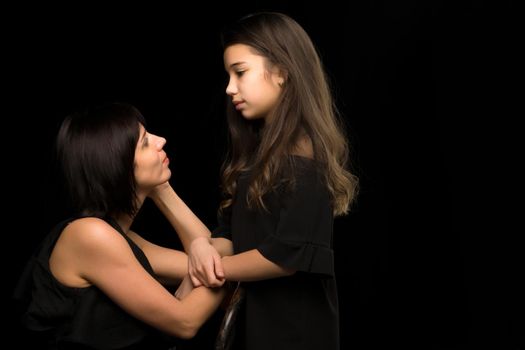 Happy family mom and daughter in the studio on a black background. The concept of love, childhood.