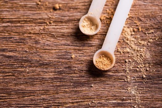 Mineral powder of different colors with spoon dispenser for make-up on wooden background.