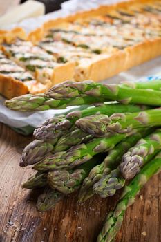 Asparagus for home made asparagus savory tart with pecorino and bacon on old wooden background. Selective focus.