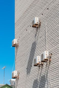 Air conditioning equipment for cooling of the air modern technologies on the wall of a white brick building against the blue sky.